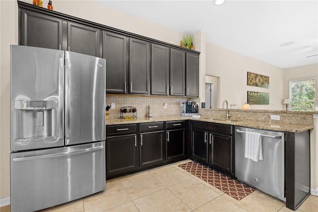 727 Grape Ivy Ln, New Smyrna Beach, FL 32168 - kitchen with stainless steel appliances, light tile patterned floors, dark cabinetry, a peninsula, and light stone counters