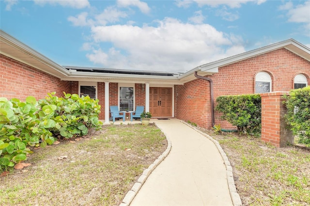 2724 N Halifax Ave, Daytona Beach, FL 32118 - doorway to property with brick siding, covered porch, and solar panels