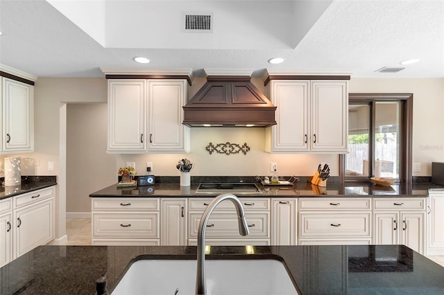 1261 Burning Tree Ln, Winter Park, FL 32792 - kitchen featuring premium range hood, black electric stovetop, dark stone counters, recessed lighting, and white cabinets