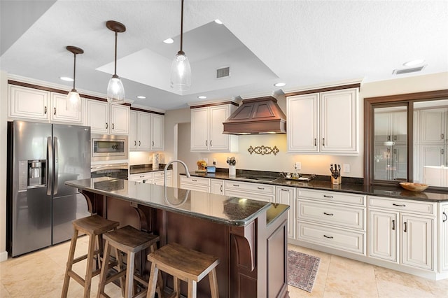 1261 Burning Tree Ln, Winter Park, FL 32792 - kitchen with appliances with stainless steel finishes, custom range hood, dark countertops, recessed lighting, and a center island with sink