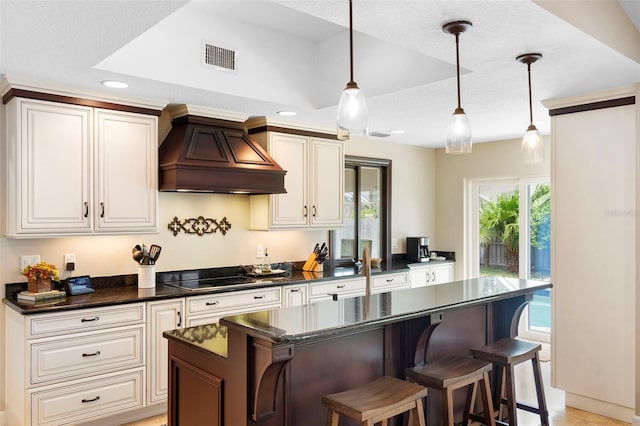 1261 Burning Tree Ln, Winter Park, FL 32792 - kitchen with custom exhaust hood, black electric cooktop, a center island, decorative light fixtures, and a kitchen bar
