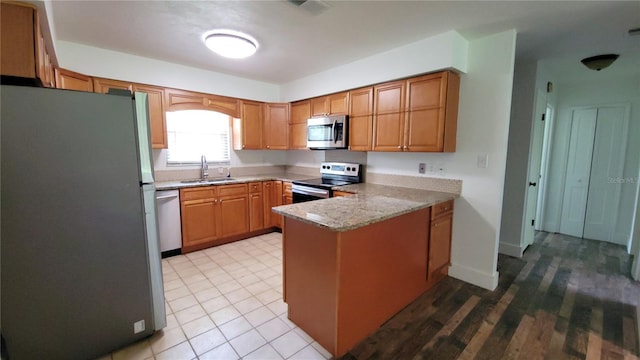 1513 S Elsasser St, Deland, FL 32720 - kitchen with appliances with stainless steel finishes, a peninsula, light stone counters, and brown cabinets