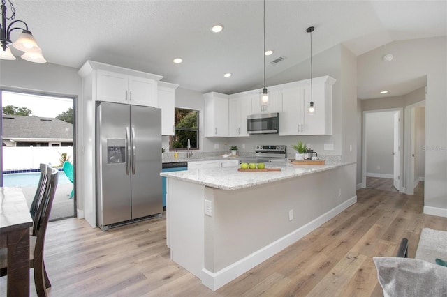 3117 Pine Tree Dr, Edgewater, FL 32141 - kitchen with appliances with stainless steel finishes, white cabinetry, vaulted ceiling, light wood-type flooring, and light stone counters