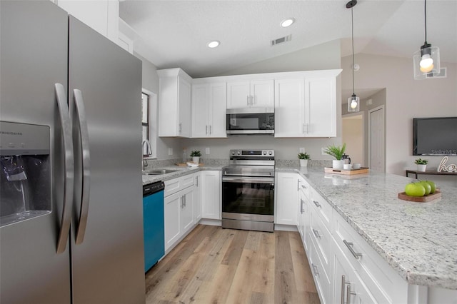 3117 Pine Tree Dr, Edgewater, FL 32141 - kitchen featuring appliances with stainless steel finishes, vaulted ceiling, a peninsula, white cabinets, and light wood-style flooring