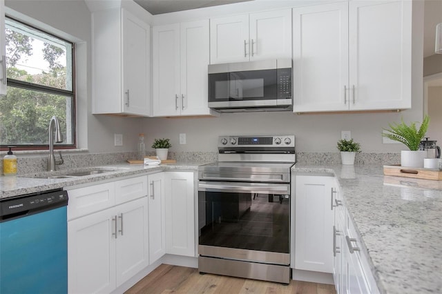3117 Pine Tree Dr, Edgewater, FL 32141 - kitchen featuring stainless steel appliances, white cabinetry, light stone countertops, and light wood-style floors
