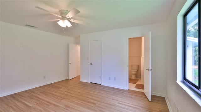 1017 Chippewa Trl, Daytona Beach, FL 32117 - unfurnished bedroom featuring multiple windows, light wood-style flooring, ensuite bathroom, and a ceiling fan