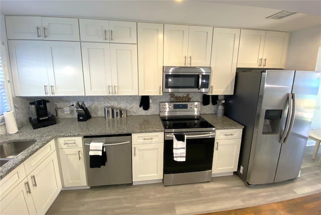 4786 S Atlantic Ave Unit 3, Ponce Inlet, FL 32127 - kitchen featuring stainless steel appliances, white cabinetry, decorative backsplash, and stone countertops