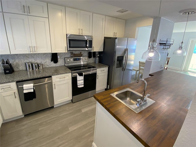 4786 S Atlantic Ave Unit 3, Ponce Inlet, FL 32127 - kitchen featuring stainless steel appliances, wooden counters, light wood-style flooring, backsplash, and white cabinets