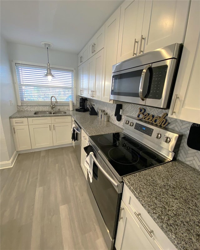 4786 S Atlantic Ave Unit 3, Ponce Inlet, FL 32127 - kitchen featuring stainless steel appliances, white cabinetry, stone countertops, backsplash, and light wood-style flooring