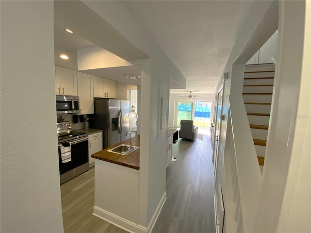 4786 S Atlantic Ave Unit 3, Ponce Inlet, FL 32127 - kitchen with stainless steel appliances, wooden counters, light wood finished floors, backsplash, and white cabinetry