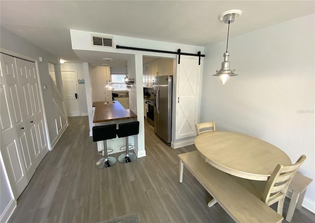 4786 S Atlantic Ave Unit 3, Ponce Inlet, FL 32127 - kitchen with stainless steel fridge with ice dispenser, dark wood-style flooring, a barn door, and hanging light fixtures