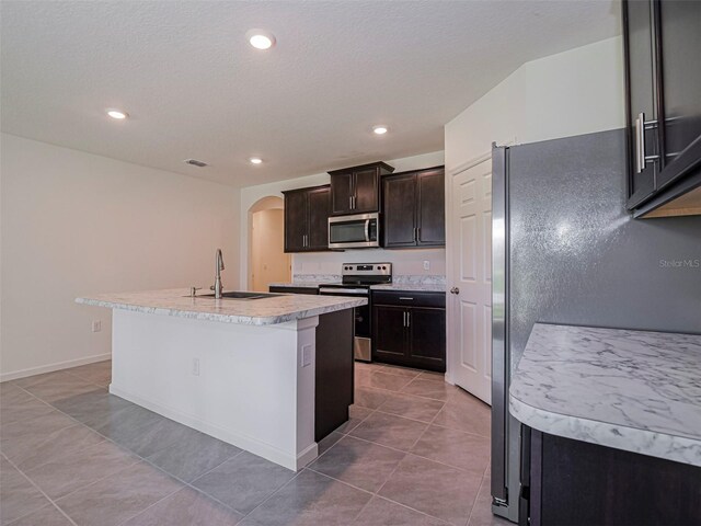 1915 Ganyard Ave SW, Palm Bay, FL 32908 - kitchen featuring appliances with stainless steel finishes, arched walkways, light countertops, an island with sink, and tile patterned floors