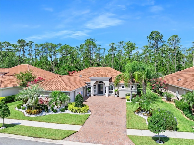 2825 S Asciano Ct, New Smyrna Beach, FL 32168 - view of front of house featuring an attached garage, decorative driveway, a front lawn, a tile roof, and stucco siding