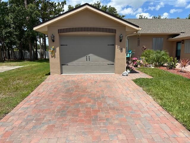 118 Tuscany Villas Dr, Edgewater, FL 32141 - view of front facade with stucco siding, a front lawn, decorative driveway, and a garage