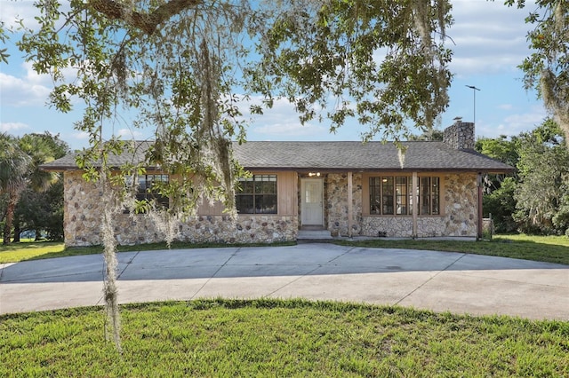 5759 Dogwood Rd, Port Orange, FL 32127 - single story home with stone siding, a front lawn, a chimney, and curved driveway