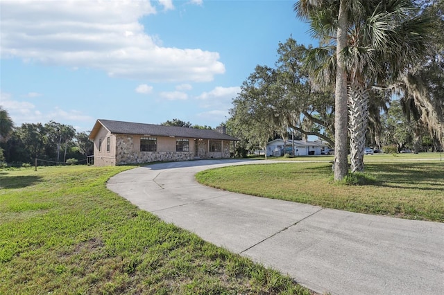 5759 Dogwood Rd, Port Orange, FL 32127 - ranch-style home featuring stone siding, curved driveway, a front lawn, and stucco siding