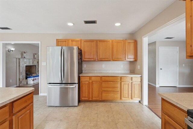 5759 Dogwood Rd, Port Orange, FL 32127 - kitchen featuring freestanding refrigerator, light countertops, light tile patterned flooring, recessed lighting, and a tiled fireplace