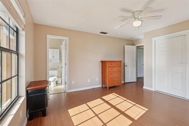 5759 Dogwood Rd, Port Orange, FL 32127 - unfurnished bedroom featuring multiple windows, wood finished floors, ensuite bath, and a ceiling fan