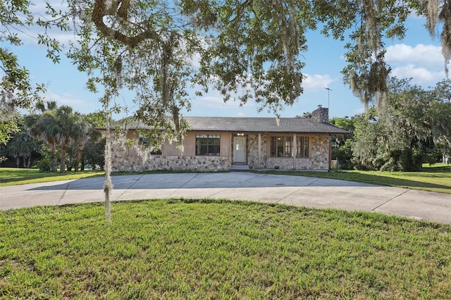 5759 Dogwood Rd, Port Orange, FL 32127 - ranch-style house featuring stone siding, a chimney, curved driveway, and a front yard