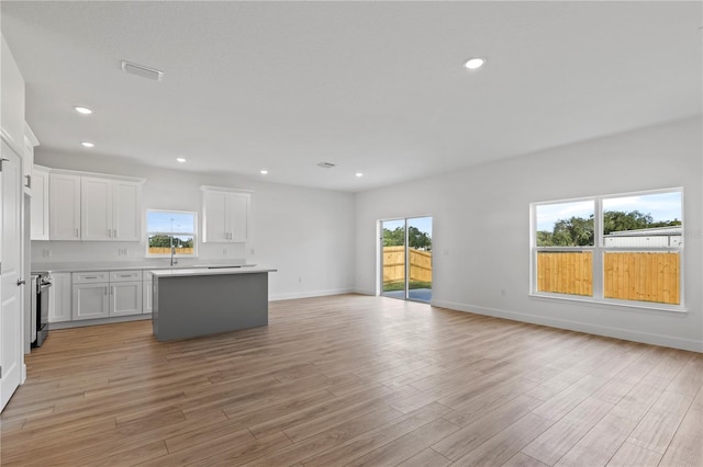 822 W 24th St, Sanford, FL 32771 - kitchen featuring open floor plan, a center island, light wood-type flooring, white cabinetry, and light countertops
