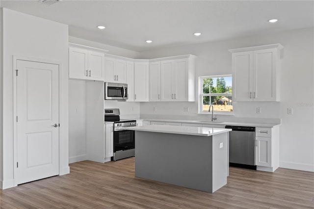 822 W 24th St, Sanford, FL 32771 - kitchen with appliances with stainless steel finishes, light countertops, white cabinetry, a kitchen island, and light wood-style floors