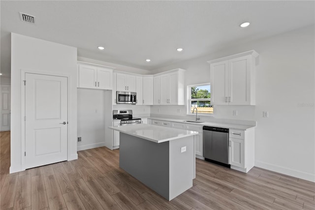 822 W 24th St, Sanford, FL 32771 - kitchen with appliances with stainless steel finishes, light wood-type flooring, white cabinetry, and recessed lighting