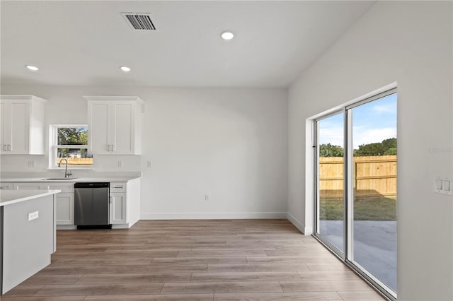 822 W 24th St, Sanford, FL 32771 - kitchen with stainless steel dishwasher, light countertops, white cabinets, light wood finished floors, and recessed lighting