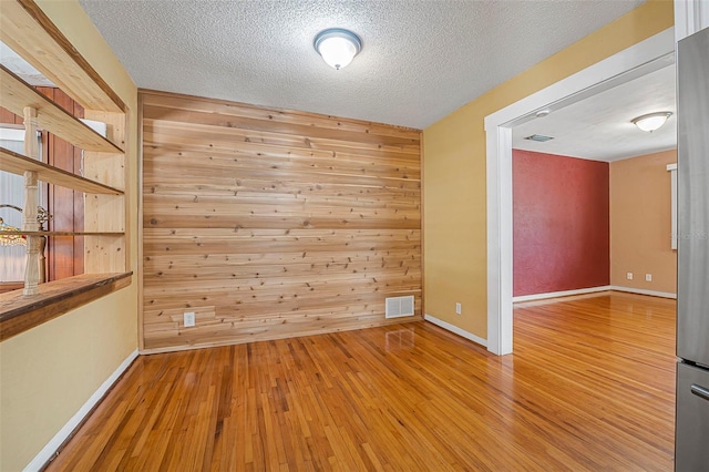 1085 Indigo Rd, Ormond Beach, FL 32174 - empty room with wood-type flooring, a textured ceiling, and wood walls