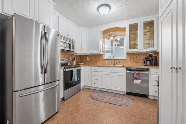 1085 Indigo Rd, Ormond Beach, FL 32174 - kitchen featuring appliances with stainless steel finishes, white cabinetry, a textured ceiling, tasteful backsplash, and light countertops