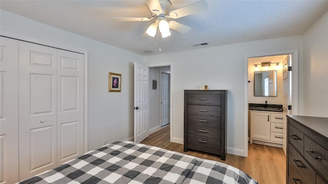 2970 Lantern Dr, South Daytona, FL 32119 - bedroom with light wood-style flooring, a closet, ensuite bath, ceiling fan, and a textured ceiling
