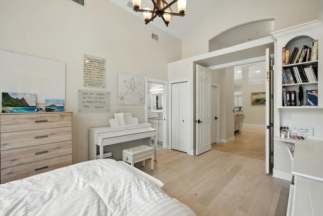 19 Tomoka Cove Way, Ormond Beach, FL 32174 - bedroom featuring a chandelier, light wood-style floors, connected bathroom, and high vaulted ceiling