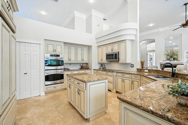 19 Tomoka Cove Way, Ormond Beach, FL 32174 - kitchen with appliances with stainless steel finishes, cream cabinetry, crown molding, stone countertops, and arched walkways