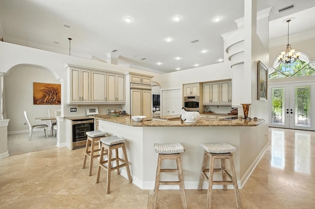 19 Tomoka Cove Way, Ormond Beach, FL 32174 - kitchen with cream cabinetry, beverage cooler, a breakfast bar area, light stone counters, and recessed lighting