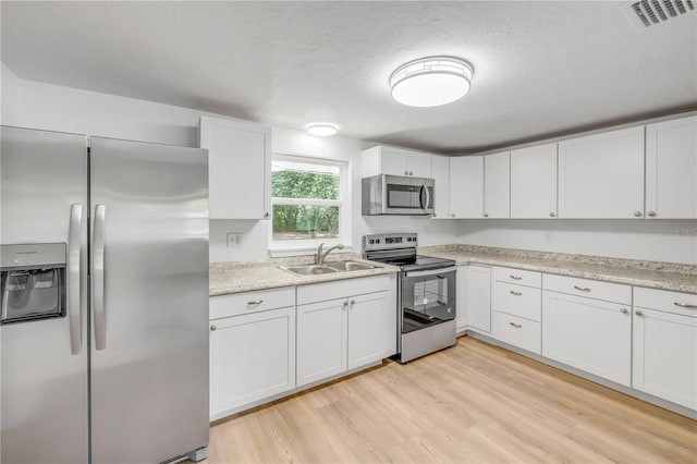173 Cedar Ave, Orange City, FL 32763 - kitchen featuring stainless steel appliances, white cabinets, light wood-type flooring, and a textured ceiling