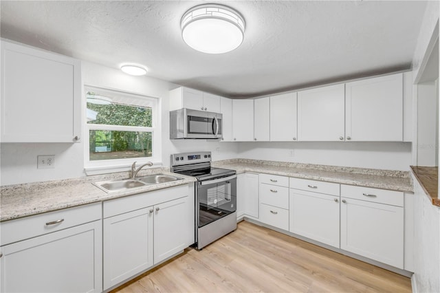 173 Cedar Ave, Orange City, FL 32763 - kitchen with stainless steel appliances, white cabinets, light wood-style floors, and a textured ceiling