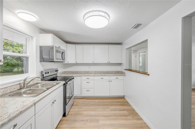 173 Cedar Ave, Orange City, FL 32763 - kitchen featuring stainless steel appliances, white cabinets, light wood finished floors, light countertops, and a textured ceiling