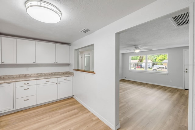 173 Cedar Ave, Orange City, FL 32763 - kitchen featuring a textured ceiling, light wood-type flooring, light countertops, and white cabinetry
