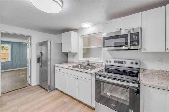 173 Cedar Ave, Orange City, FL 32763 - kitchen featuring stainless steel appliances, light wood-style floors, white cabinets, and a textured ceiling