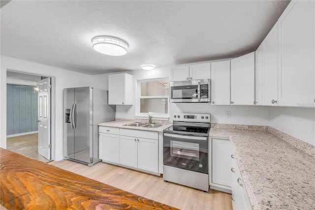 173 Cedar Ave, Orange City, FL 32763 - kitchen with appliances with stainless steel finishes, white cabinets, light wood-style flooring, and a textured ceiling