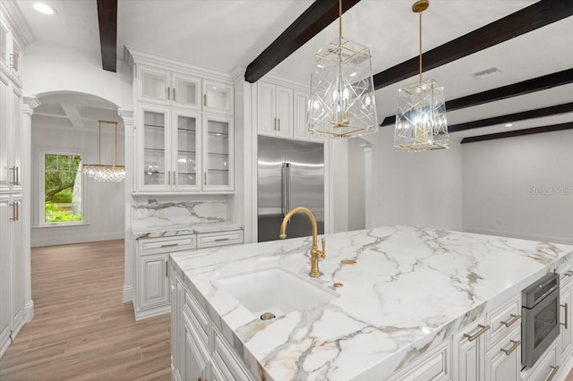 4885 State Road 11, De Leon Springs, FL 32130 - kitchen with built in appliances, beam ceiling, arched walkways, a chandelier, and light wood-style flooring