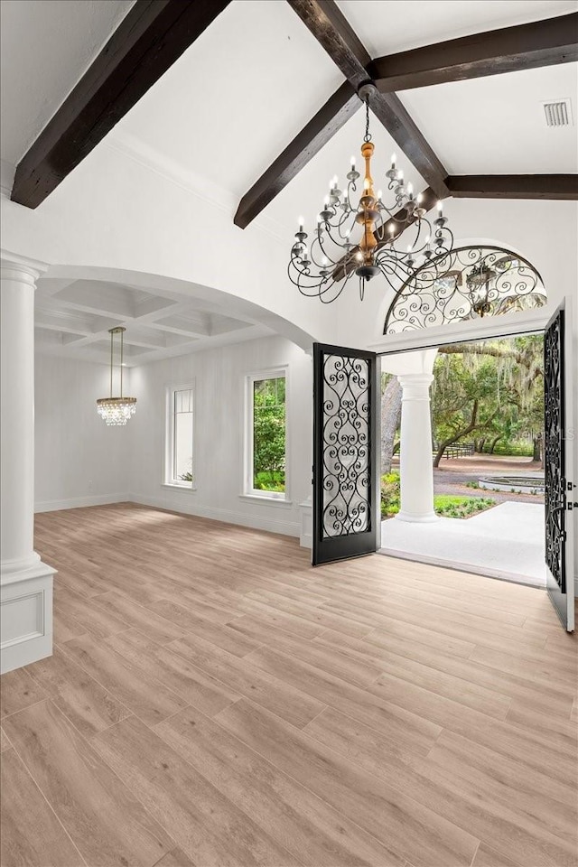 4885 State Road 11, De Leon Springs, FL 32130 - unfurnished living room with a chandelier, beam ceiling, ornate columns, light wood-style floors, and arched walkways