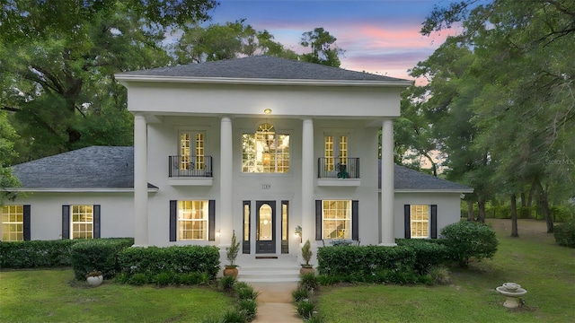 1155 Taylor Rd E, Deland, FL 32724 - greek revival house featuring a balcony, a shingled roof, and stucco siding