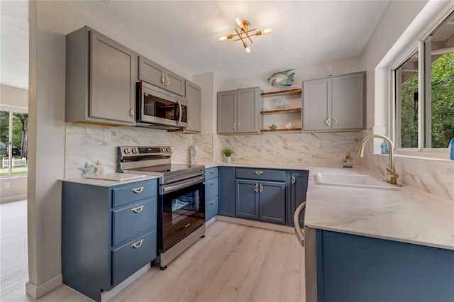 182 Grove St, Ormond Beach, FL 32174 - kitchen featuring appliances with stainless steel finishes, open shelves, light wood-style flooring, backsplash, and blue cabinets