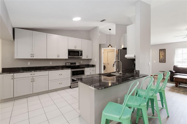5 Bird Of Paradise Pl, Palm Coast, FL 32137 - kitchen featuring stainless steel appliances, vaulted ceiling, dark stone counters, a peninsula, and a breakfast bar area