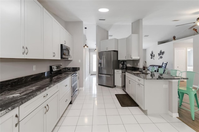 5 Bird Of Paradise Pl, Palm Coast, FL 32137 - kitchen featuring stainless steel appliances, a peninsula, lofted ceiling, dark stone countertops, and light tile patterned floors
