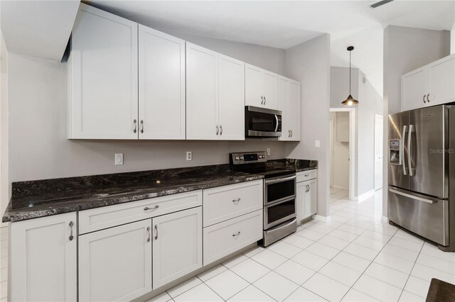 5 Bird Of Paradise Pl, Palm Coast, FL 32137 - kitchen featuring appliances with stainless steel finishes, white cabinetry, dark stone countertops, decorative light fixtures, and light tile patterned floors