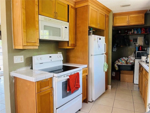 1025 Persian St, Deltona, FL 32725 - kitchen with white appliances, light tile patterned floors, and brown cabinetry