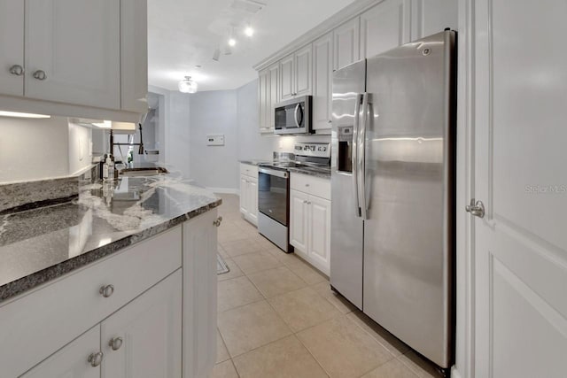 424 Luna Bella Ln Unit 330, New Smyrna Beach, FL 32168 - kitchen with stainless steel appliances, light tile patterned flooring, white cabinetry, and dark stone countertops