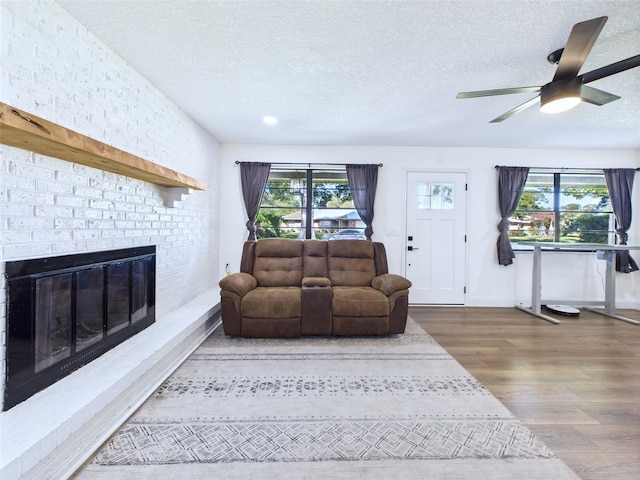 2526 Victory Palm Dr, Edgewater, FL 32141 - living room with a textured ceiling, wood finished floors, healthy amount of natural light, a fireplace, and ceiling fan