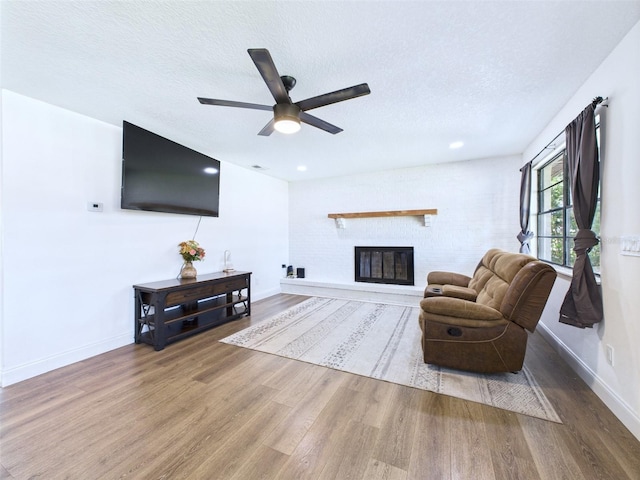 2526 Victory Palm Dr, Edgewater, FL 32141 - living area featuring wood finished floors, a ceiling fan, a textured ceiling, and a glass covered fireplace